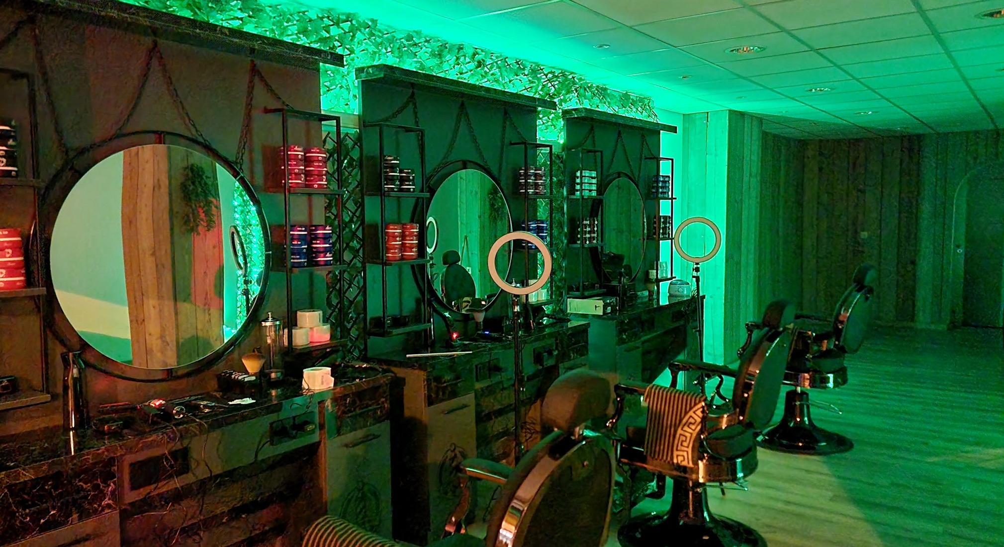 De zaak van Barbershop Mo in groen licht, met de ronde spiegels en de stoelen