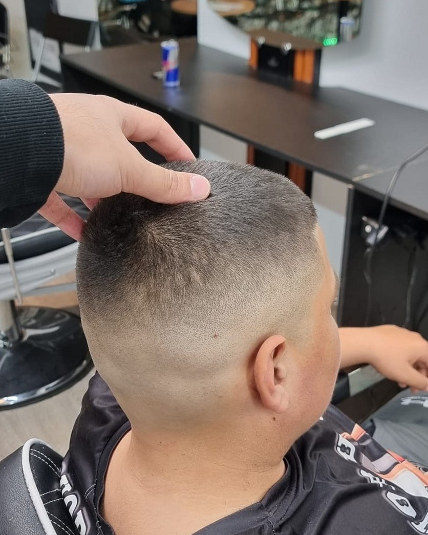 Kapper legt de laatste hand aan de fade van een jonge klant